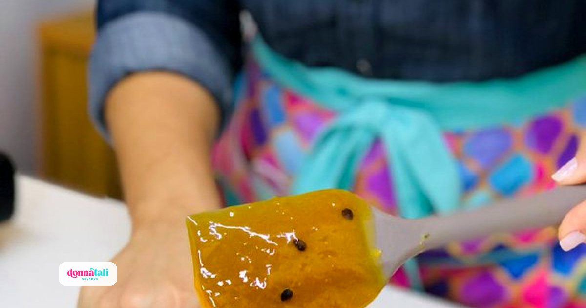 Calda de maracujá para geladinho gourmet, ainda na produção, escorrendo de uma espátula